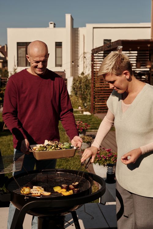 Free A couple prepares vegetable barbecue together in their backyard during a sunny day. Stock Photo