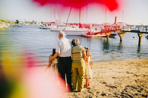 Grandparents With Their Granddaughters Standing By The Shore