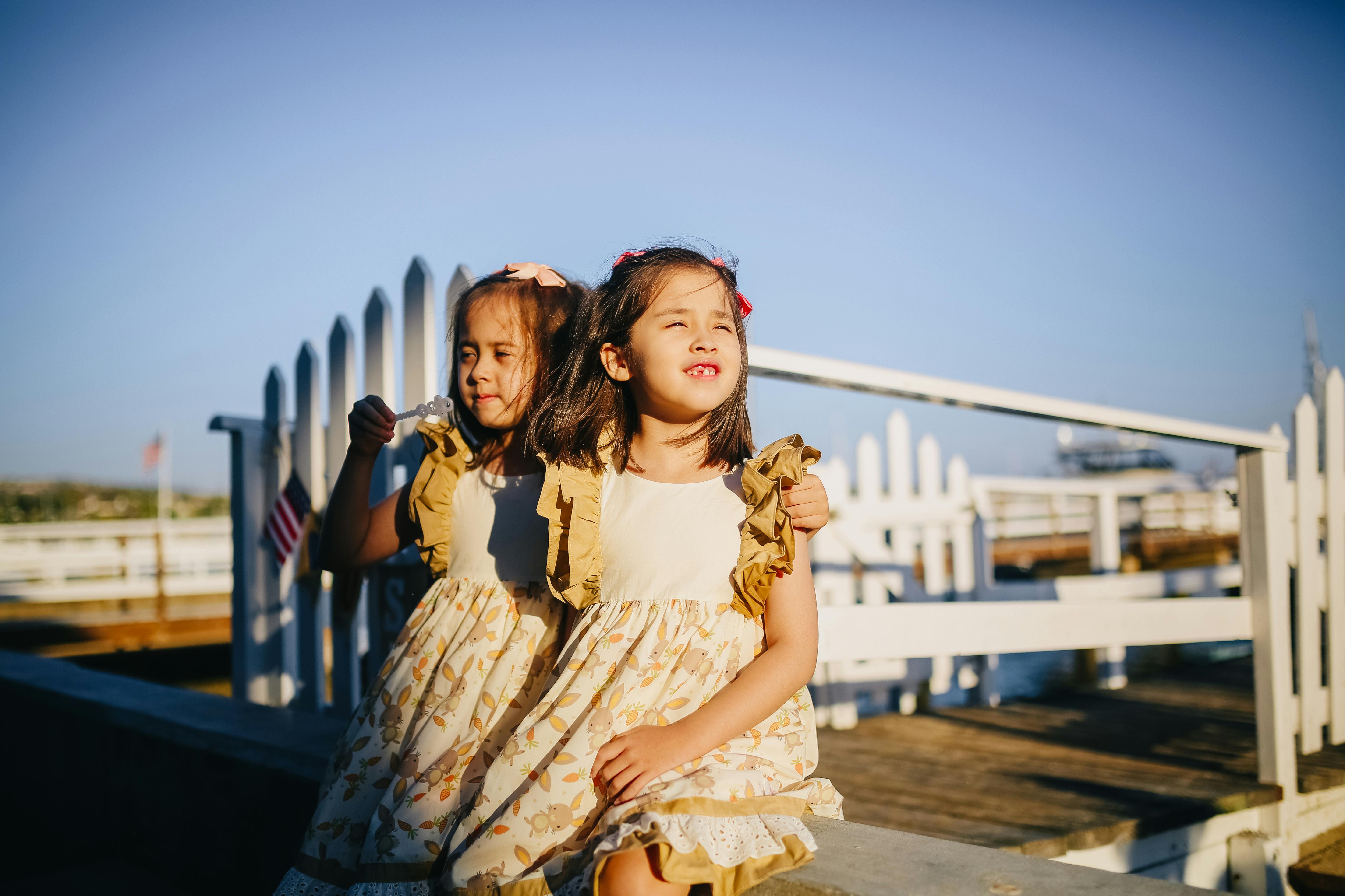 girls in white dress standing on wooden dock