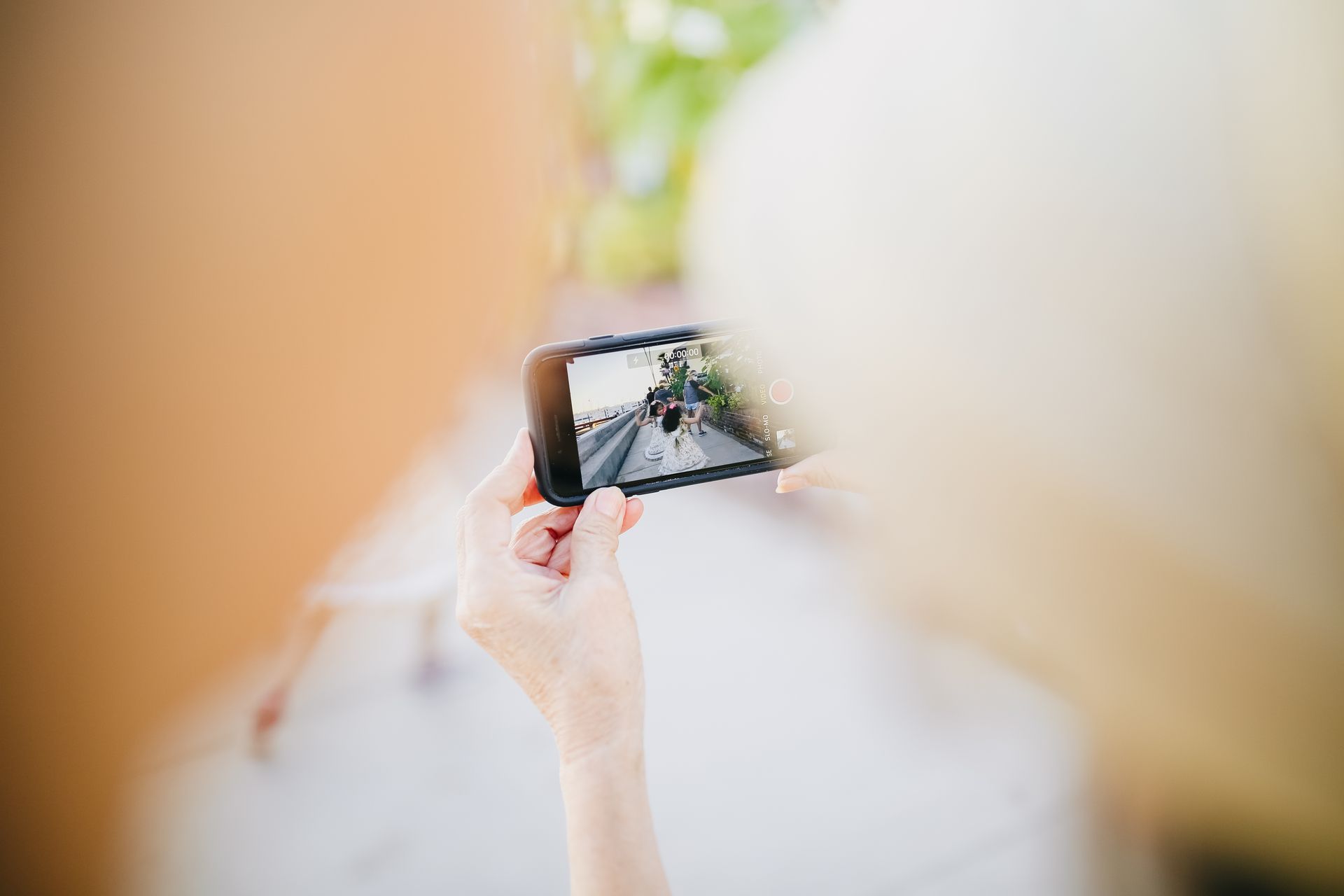 A person uses a smartphone to photograph a family gathering outdoors.