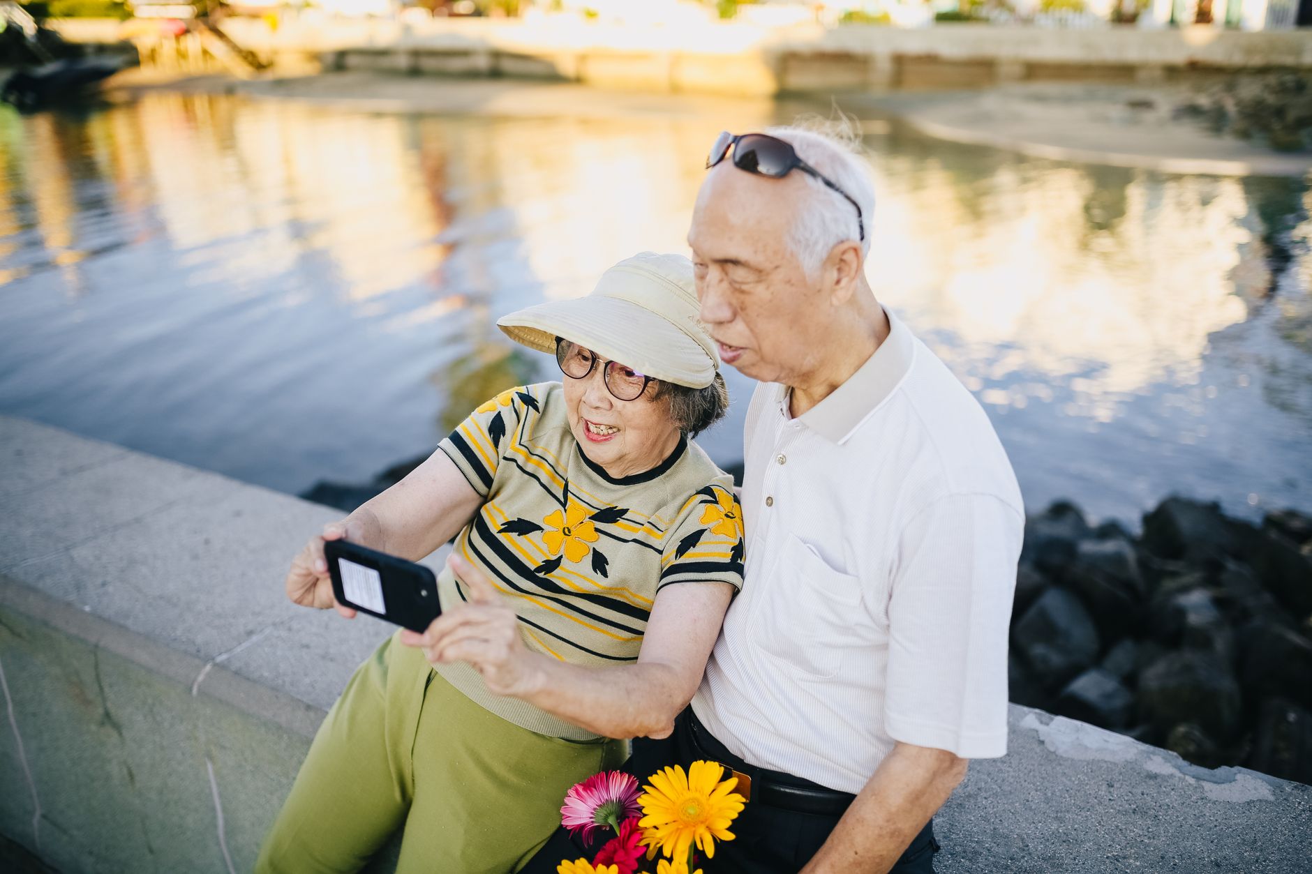 Joyful senior couple taking a selfie by the waterfront, capturing a happy moment outdoors.