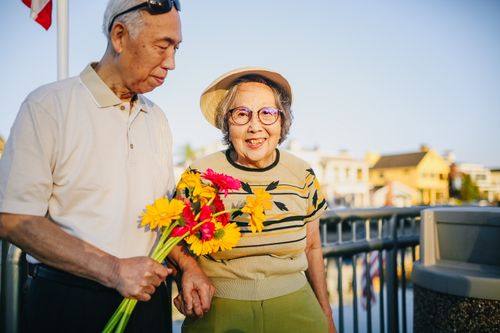 Free Happy elderly couple holding flowers outdoors, enjoying togetherness and love. Stock Photo