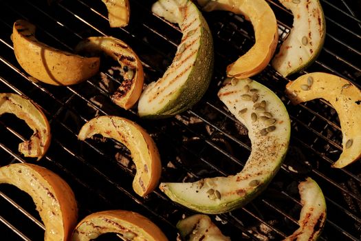 Close-up of grilled cantaloupe and melon slices on a barbecue grill outdoors in summer.