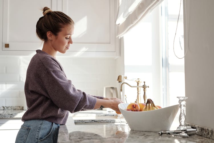 Woman Washing Fruits In The Sink