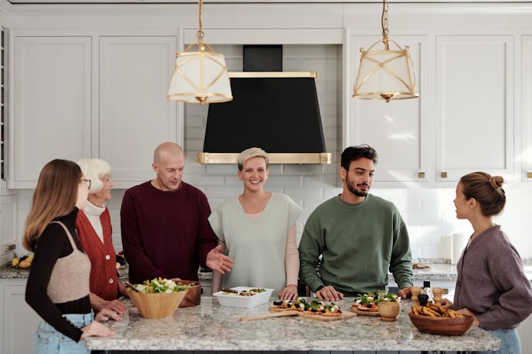 A Family Talking While Standing In The Kitchen