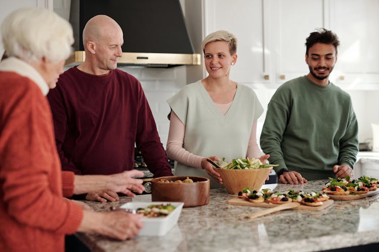 A Family Talking While Standing In The Kitchen