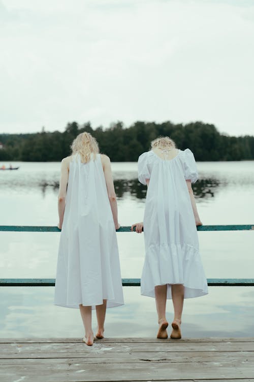 Free Back View of Twin Sisters Standing Barefoot on Dock Stock Photo