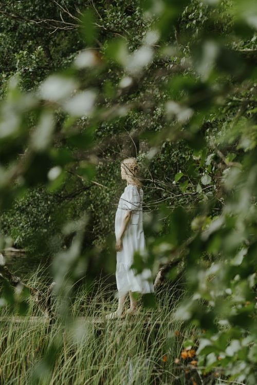 Free A serene moment of a woman in a white dress standing in the forest. Stock Photo