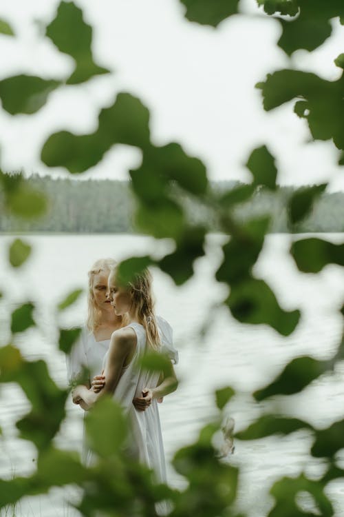 Blonde Models behind Leaves on Lakeshore