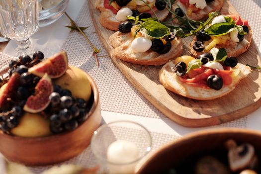 Sunlit outdoor table with Mediterranean bruschetta and fresh fruit display.