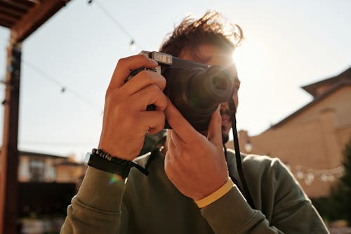 Uomo In Giacca Grigia Che Tiene La Fotocamera Reflex Digitale Nera E Argento