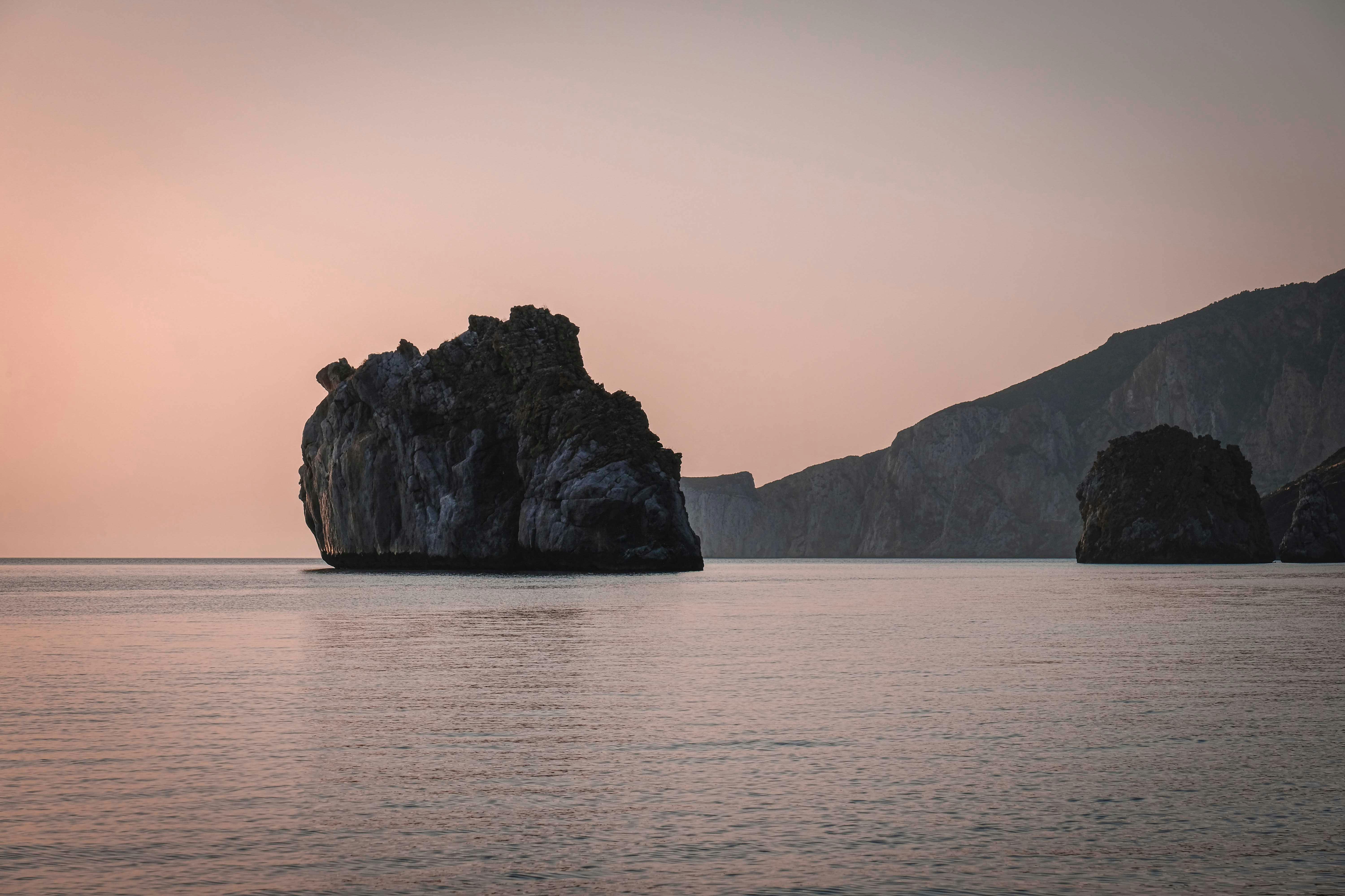 mountain and cliffs in endless sea at sundown