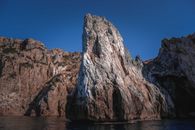 High cliff against sea under blue sky