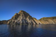 Spectacular view of Kara Dag Mountain reflecting in Black Sea in Republic of Crimea under blue sky
