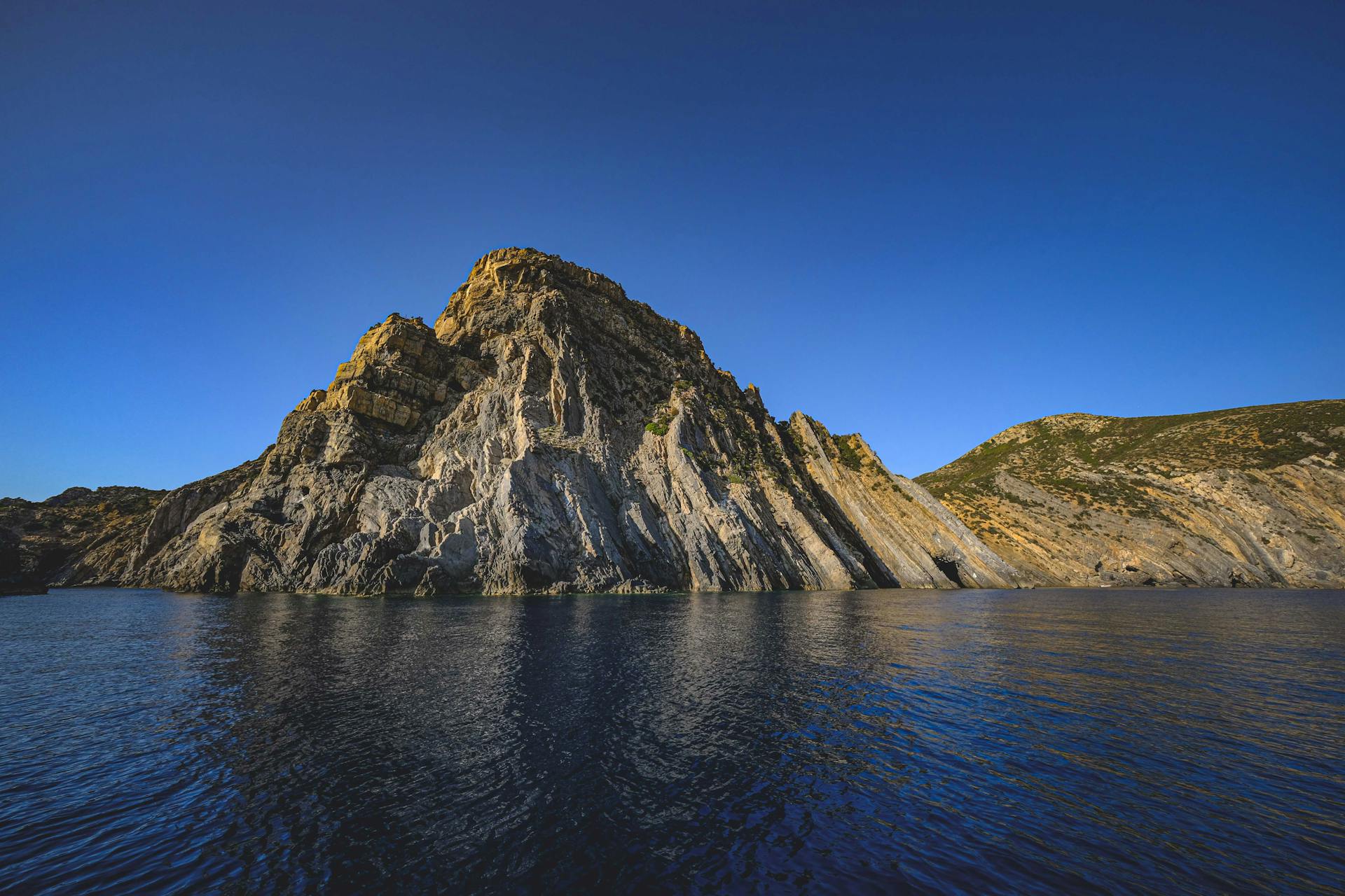 Spectacular view of Kara Dag Mountain reflecting in Black Sea in Republic of Crimea under blue sky