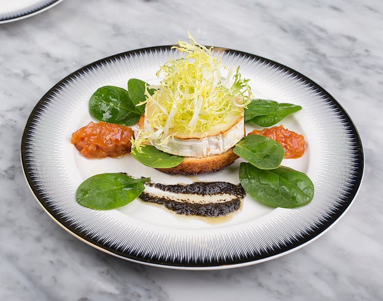 A Dish With Scallop And Spinach Leaves