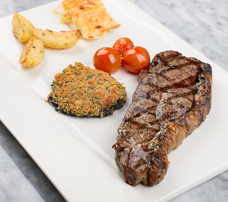 Photo Of A Dish With Grilled Steak And Potato Wedges