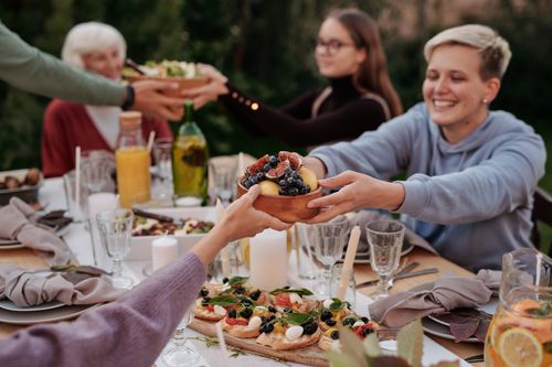 Free Joyful family gathering outdoors, featuring fruit bowls and shared meals on a beautifully set table. Stock Photo