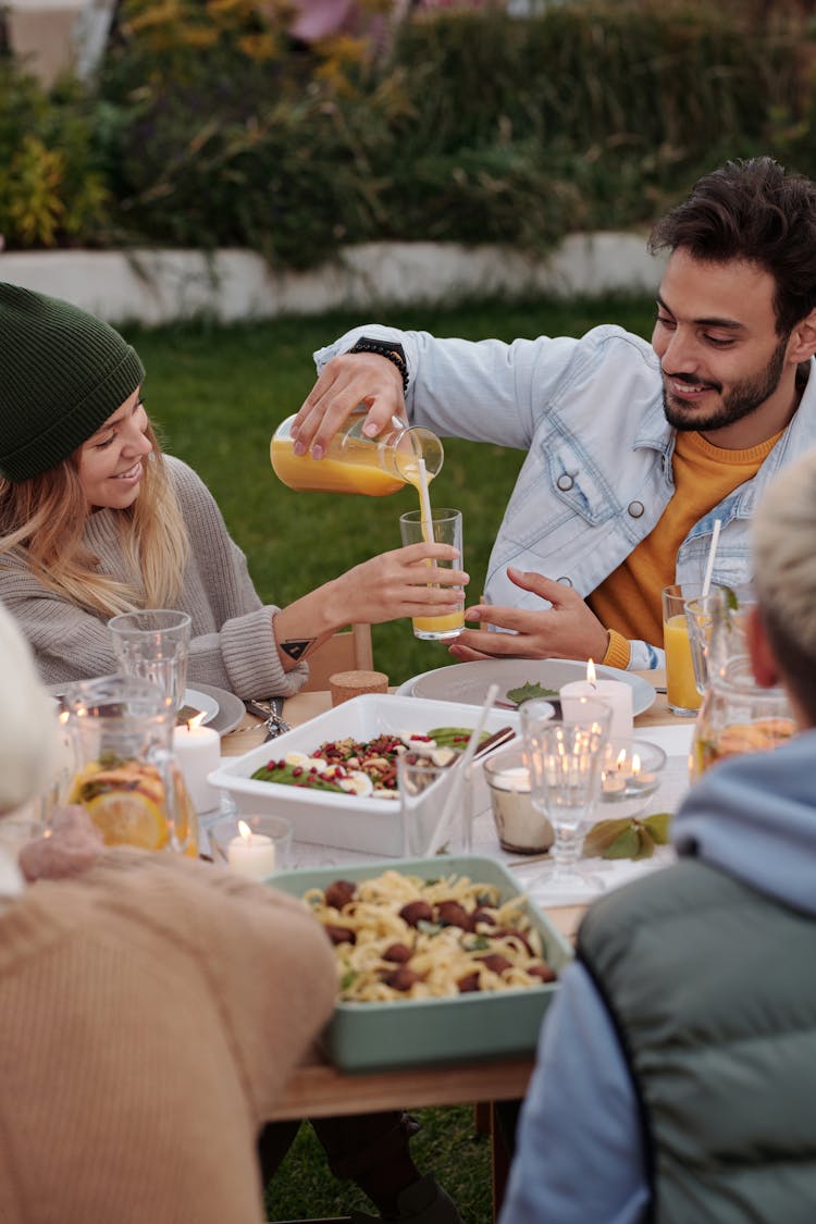 Happy Couple And Other People Enjoying Dinner And Drinks In Garden