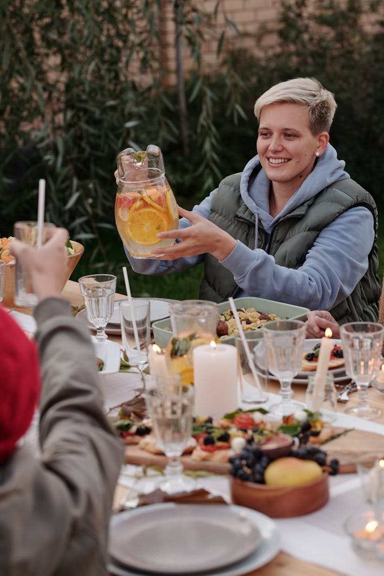 Happy Young Woman Having Dinner With Friends In Backyard