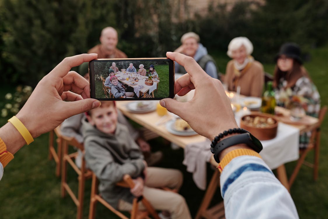 Free Unrecognizable person taking photo of family dinner on smartphone Stock Photo