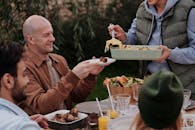 Unrecognizable woman serving delicious pasta with meatballs to man during dinner