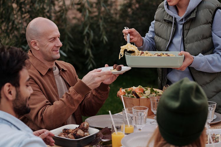 Unrecognizable Woman Serving Delicious Pasta With Meatballs To Man During Dinner