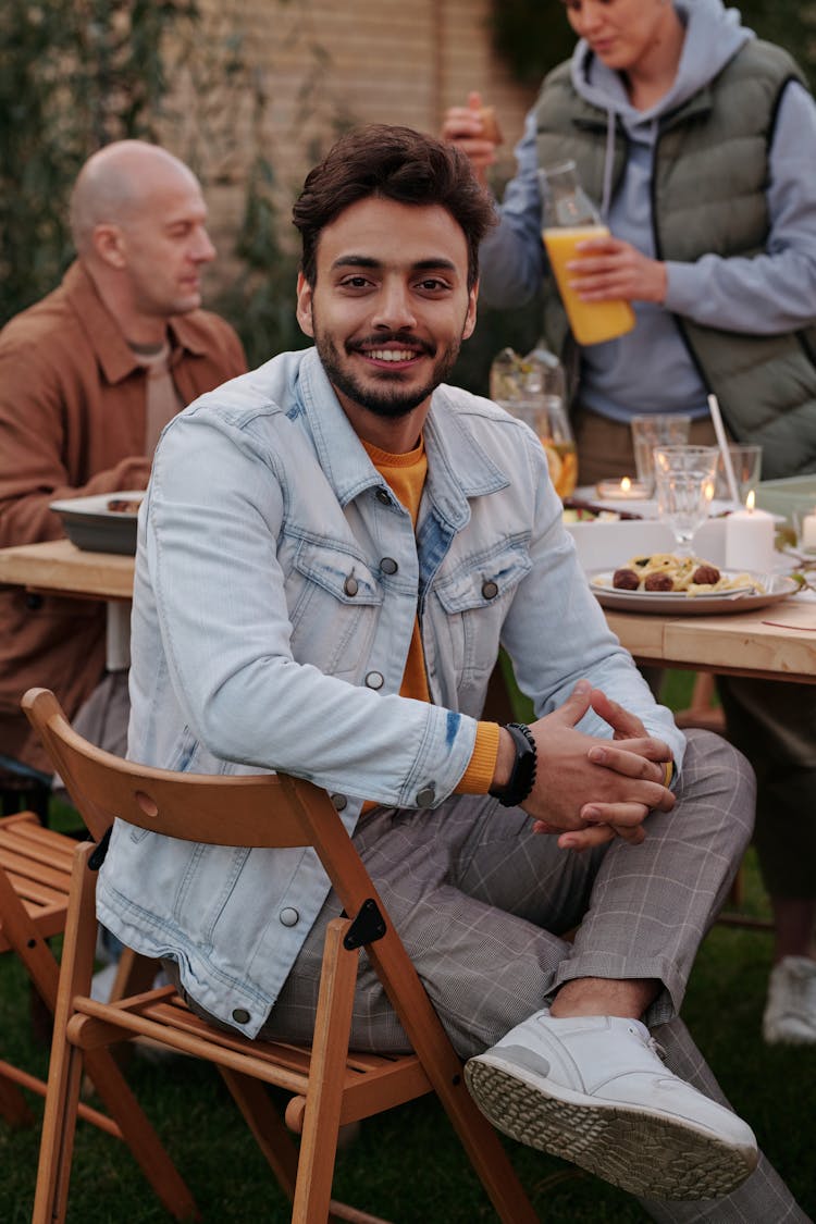 Smiling Ethnic Man At Table With Family On Picnic