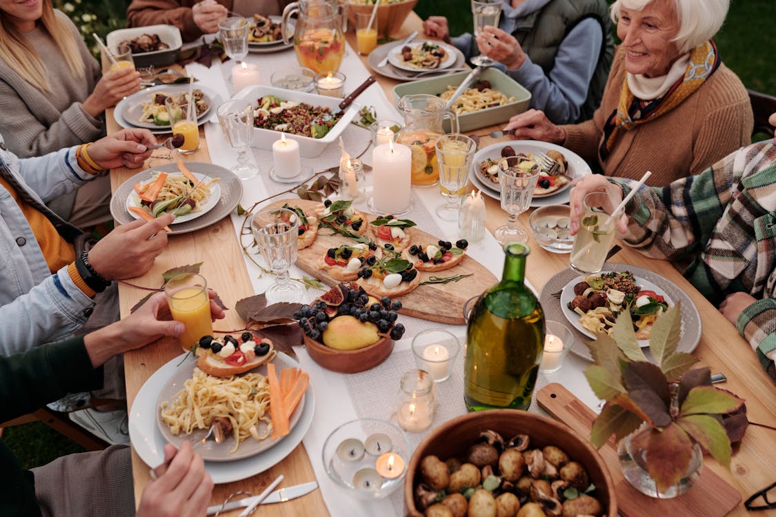 Free From above crop people enjoying festive dinner with snacks at garden table with candles burning Stock Photo