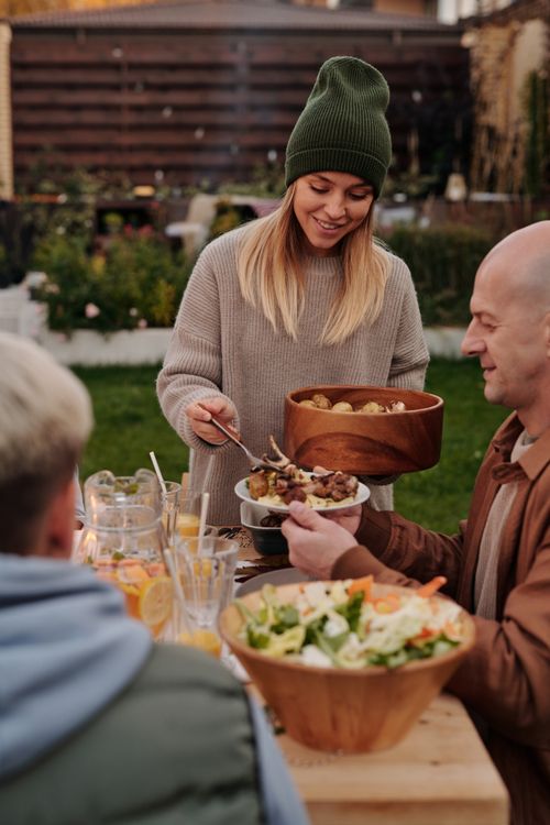 Free Joyful evening among friends sharing a meal outdoors with fresh food and laughter. Stock Photo