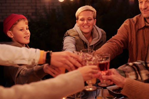 Free Cheerful crop adults and kids cheering with drinks while spending time in backyard having dinner at evening Stock Photo