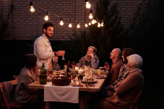 Friends sharing a long outdoor dinner under string lights — Askar Abayev on Pexels