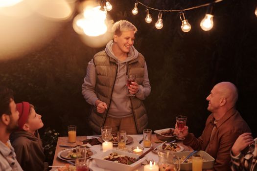 A joyful evening gathering of friends dining under string lights, sharing laughter and good food.