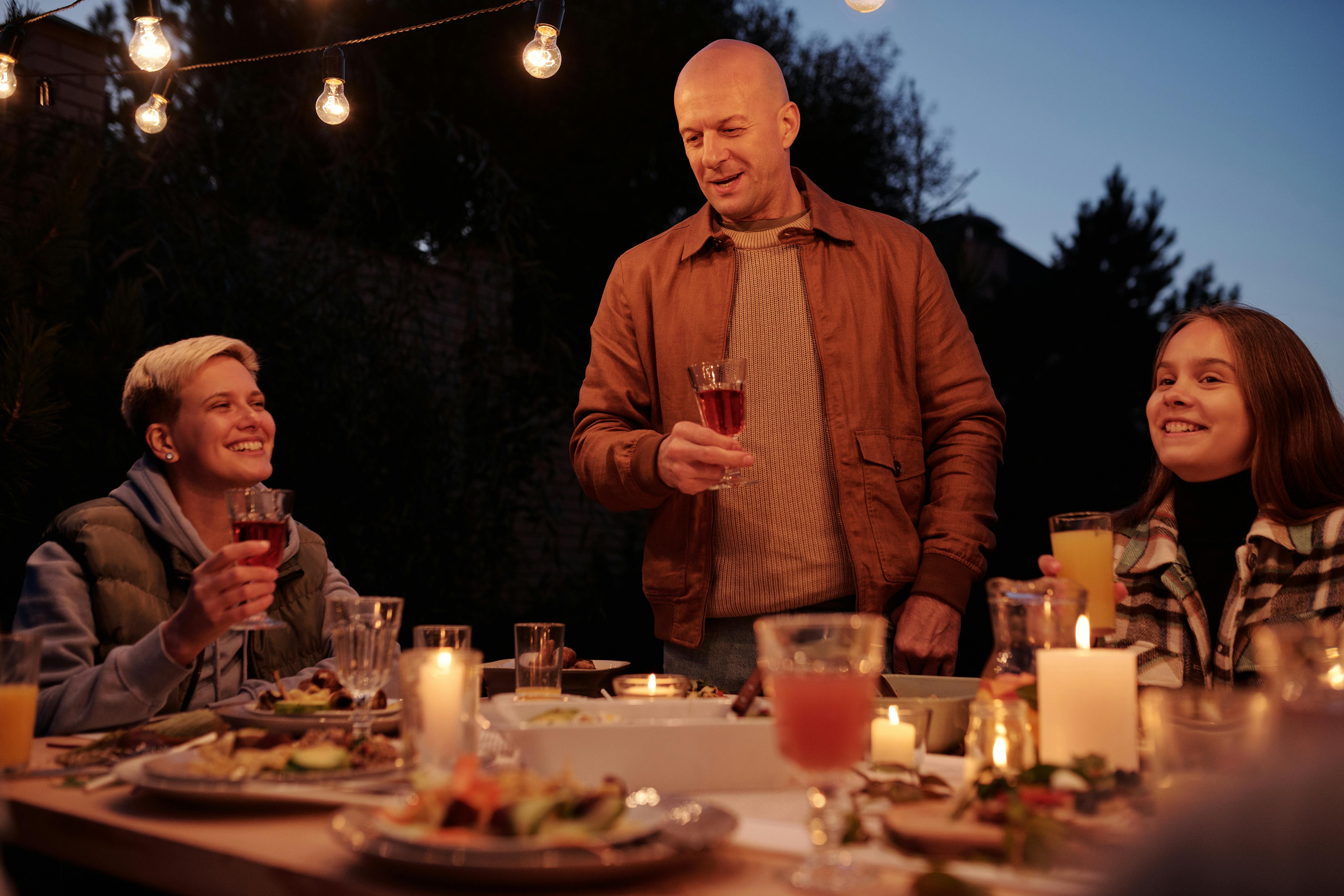 Image Name Backyard dining area with string lights and recessed sconces illuminating a fall evening meal