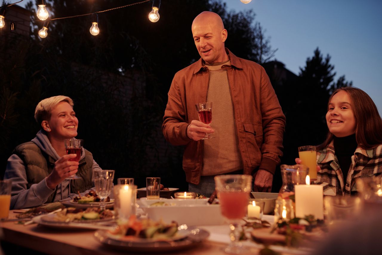 A host raising a glass at a dinner party