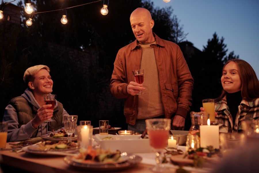 A family toasting with drinks at an evening dinner in the garden
