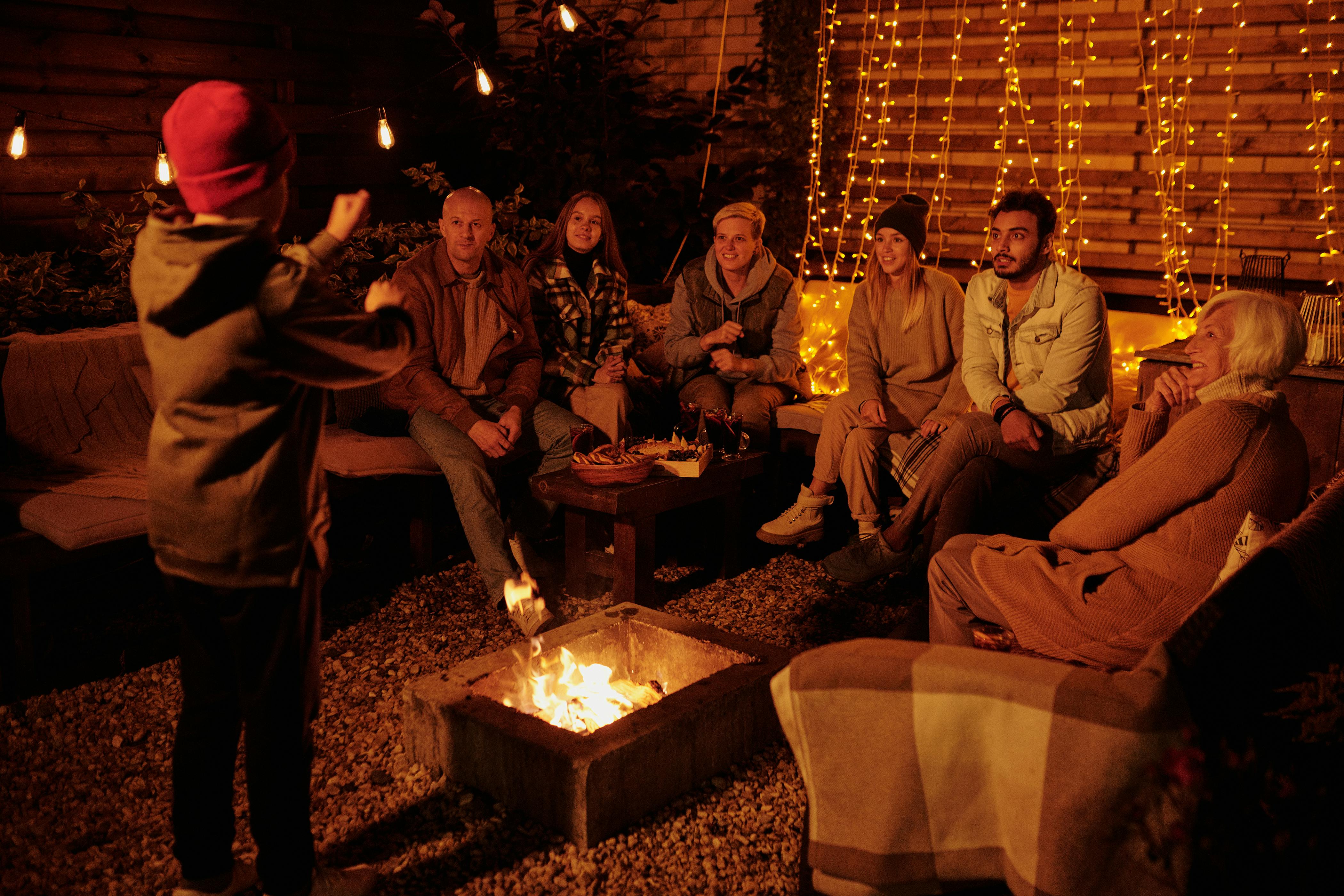 family playing charades at bonfire in garden