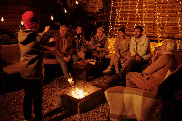 Family Playing Charades At Bonfire In Garden