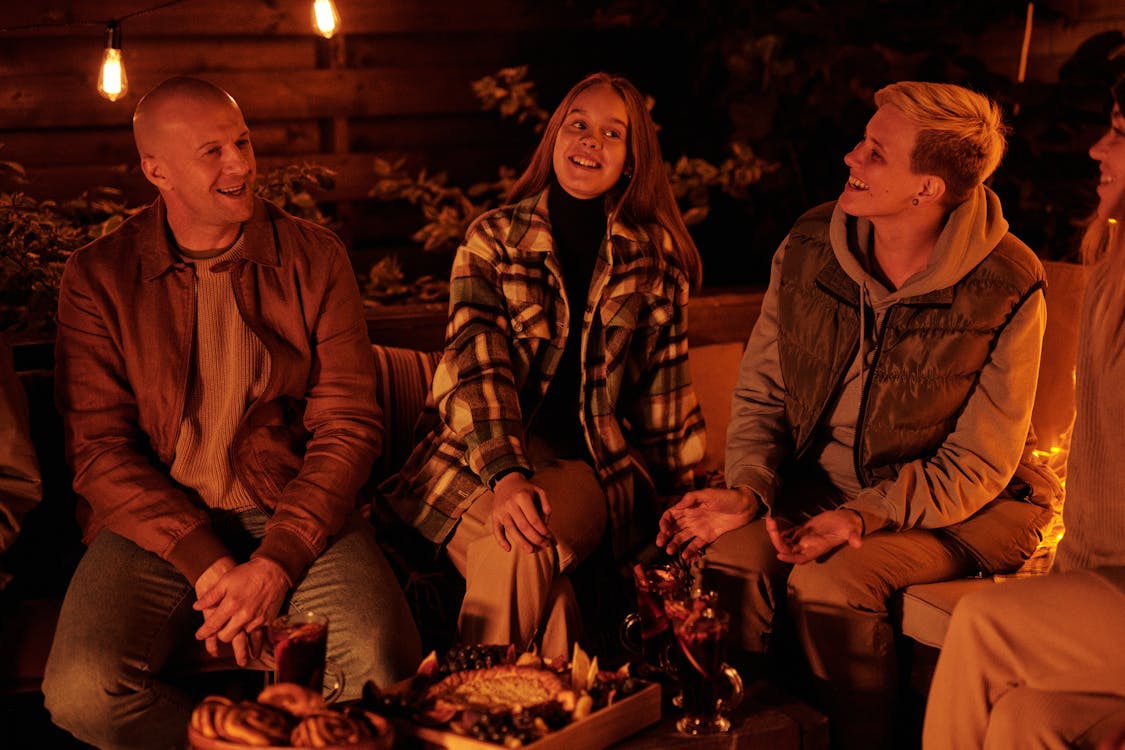 Laughing friends around bonfire in night garden