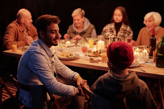 Smiling Indian man and boy chatting at festive table with family and friends during reunion