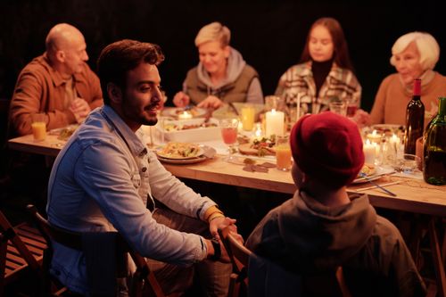 Free Smiling Indian man and boy chatting at festive table with family and friends during reunion Stock Photo