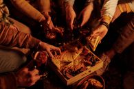 From above faceless people sharing delicious pie with sweet snacks and mulled wine enjoying night in garden