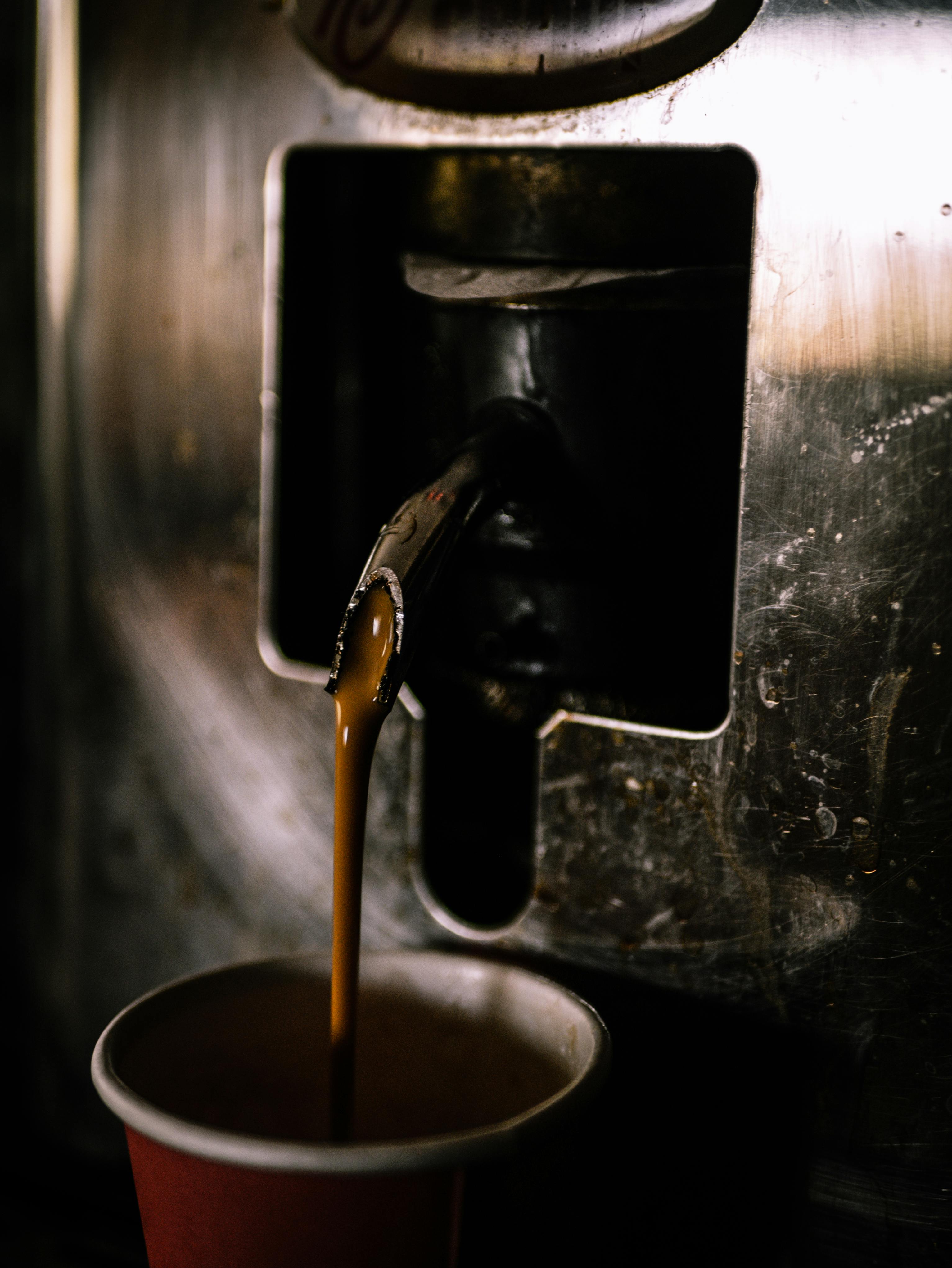 A close-up view of coffee being poured from a machine into a cup. Warm and inviting.