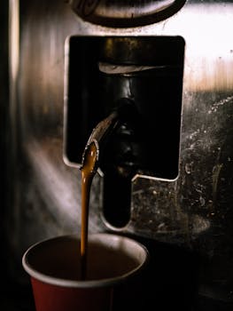 A close-up view of coffee being poured from a machine into a cup. Warm and inviting.