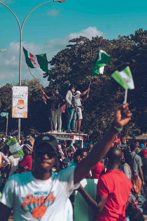 Free A group of Nigerian protesters rally outdoors holding flags and signs in a daytime demonstration. Stock Photo