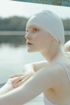 一位戴着泳帽的女人若有所思地凝视着湖边