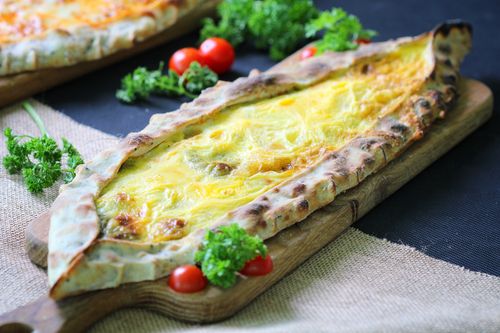 Free Tasty freshly baked Georgian khachapuri topped with cheese on a rustic wooden board. Stock Photo