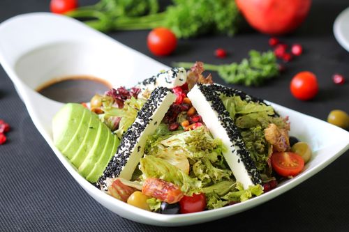 Free Close-up of a fresh salad with avocado, cheese, and vegetables in a modern dish. Stock Photo