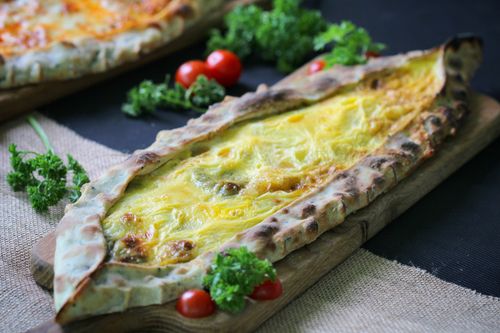 Free Tasty cheese and egg pide, surrounded by fresh parsley and cherry tomatoes, served on a wooden board. Stock Photo