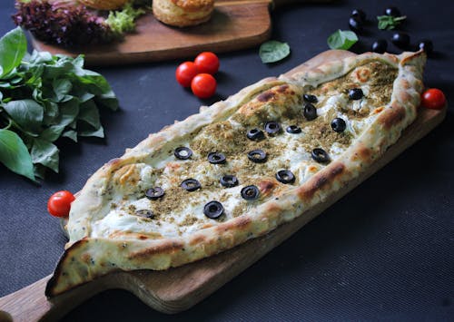 A Pizza with Sliced Olives on a Wooden Board
